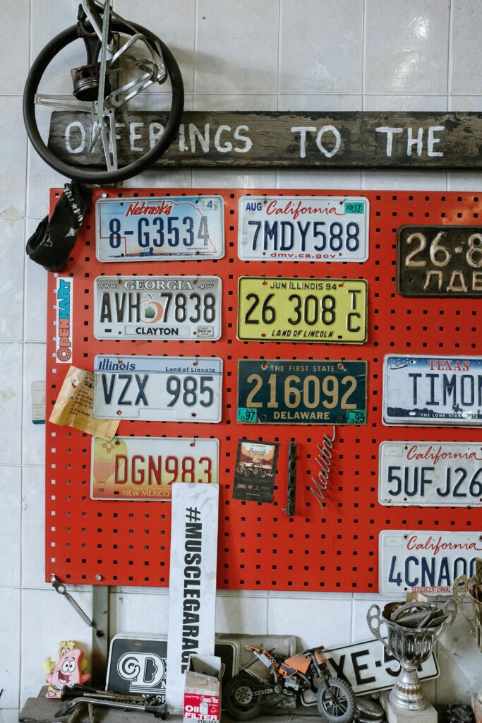 Vintage license plates from various states displayed on a workshop wall with automotive decor.