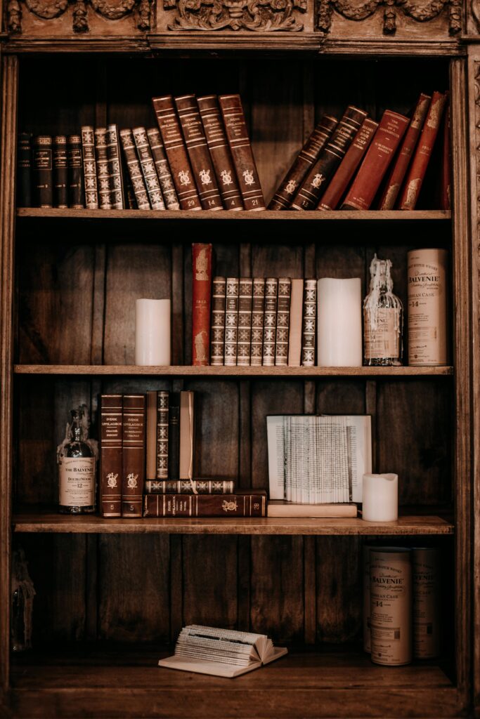 Vintage books and rustic decor on a wooden bookshelf, perfect for a classic study atmosphere.